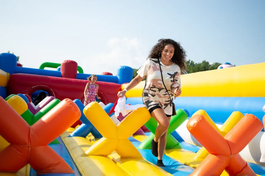 Een vrouw rent lachend over een kleurrijk springkussen